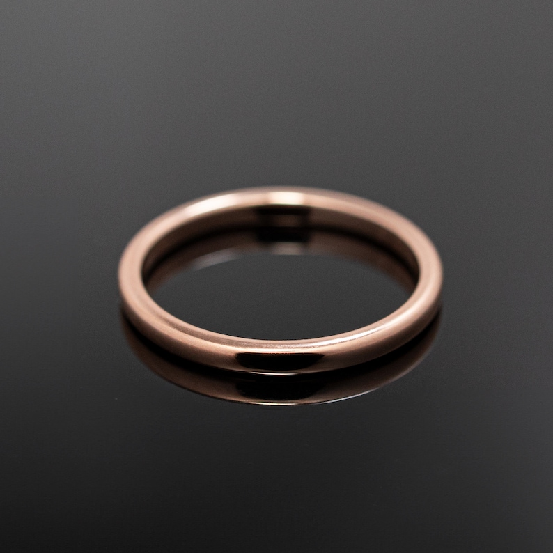 May include: A simple, thin, circular ring with a smooth, polished surface and a warm rose gold metallic finish. The band features a rounded profile and a consistent width throughout, reflecting light evenly across its curved, metallic exterior.