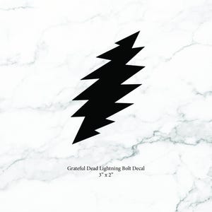 May include: Black lightning bolt decal, 3 inches by 2 inches, on a white marble background. The text "Grateful Dead Lightning Bolt Decal" is below the bolt. The decal is a stylized zig-zag shape.