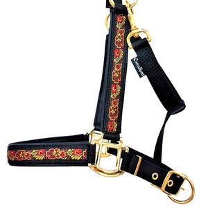 May include: Black horse halter with a red and gold floral pattern and gold hardware. The halter has the brand name "Cavaller" on the side.