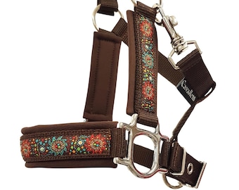 May include: A brown horse halter with decorative embroidered detailing in red, turquoise, and yellow. The halter features silver-toned metal hardware and the brand name "Cavallini" printed on a strap.