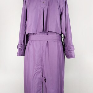 May include: A long, purple raincoat with a belt and a button closure. The raincoat has a collar and long sleeves.