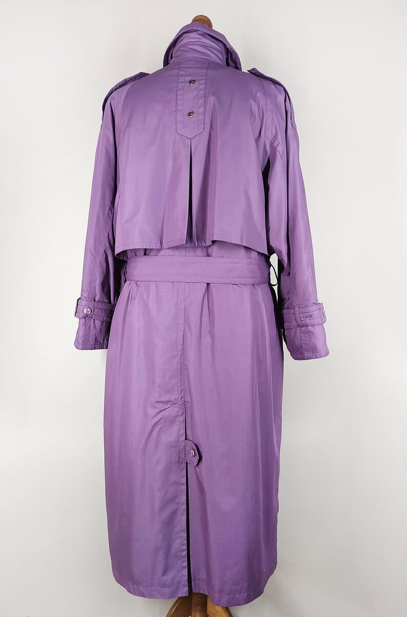 May include: A long, purple raincoat with a belt and a button closure. The raincoat has a collar and long sleeves.