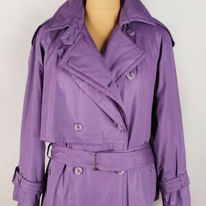 May include: A long, purple raincoat with a double-breasted closure, a belt, and a large collar.