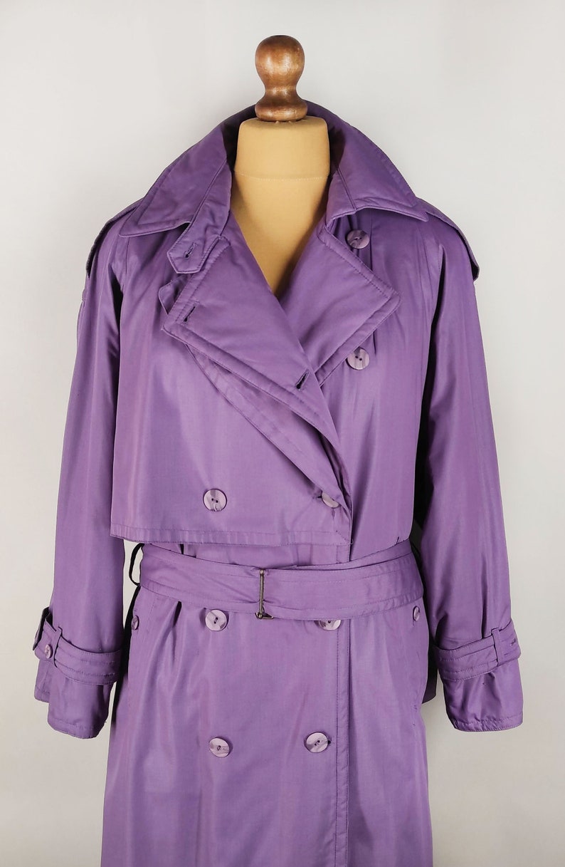 May include: A long, purple raincoat with a double-breasted closure, a belt, and a large collar.