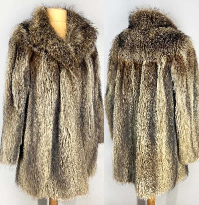 May include: A vintage fur coat in shades of brown and tan, displayed on a mannequin. The coat features a wide collar and a long, flowing design. The fur appears soft and luxurious, with a natural, textured appearance.