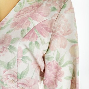 May include: A white blouse with a pink and green floral print. The fabric is soft and has a subtle sheen.