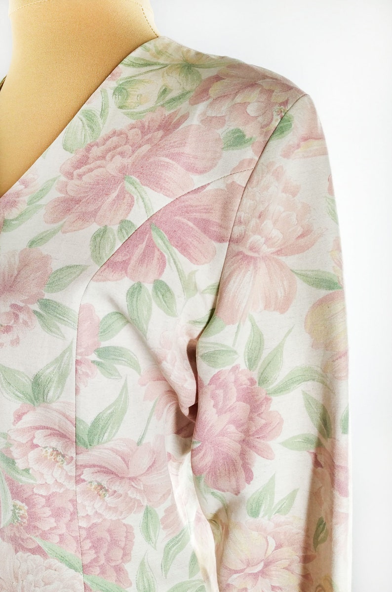 May include: A white blouse with a pink and green floral print. The fabric is soft and has a subtle sheen.