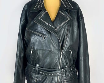 May include: Black leather jacket with silver-tone stud embellishments on the collar and lapels. Features a belted waist, multiple zippered pockets, and a diagonal zipper closure. A classic biker-style jacket.