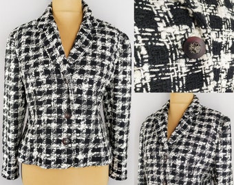 Könnte beinhalten: Schwarz-weiß kariertes Blazer mit Stehkragen und Knopfleiste. Der Blazer hat eine figurbetonte Silhouette und lange Ärmel.