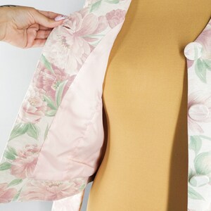 May include: A floral print jacket with a pink lining. The jacket has a button closure and is made of a lightweight fabric.