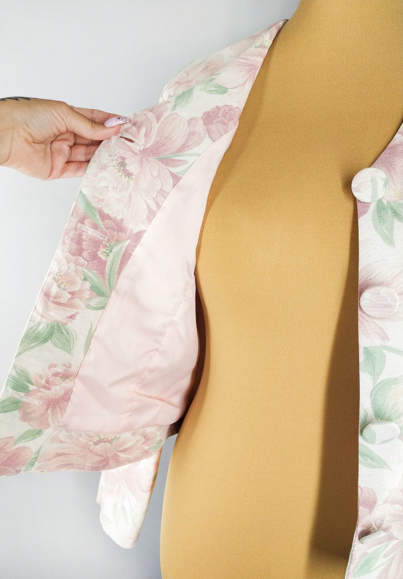 May include: A floral print jacket with a pink lining. The jacket has a button closure and is made of a lightweight fabric.