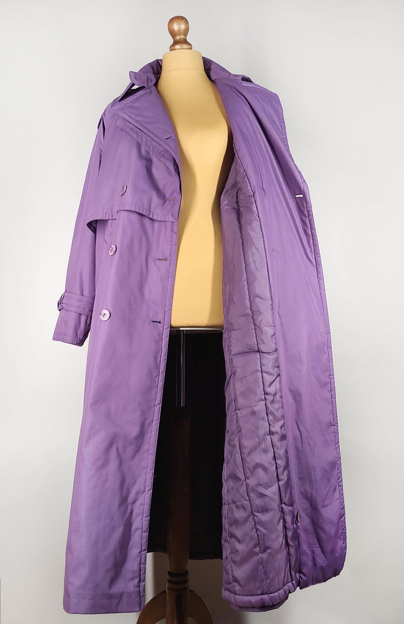 May include: A long purple coat with a double breasted closure and a quilted lining.