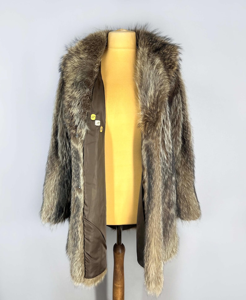 May include: A vintage fur coat with a brown and gray pattern. The coat has a wide collar and is open, revealing a brown lining. The coat is displayed on a yellow mannequin.