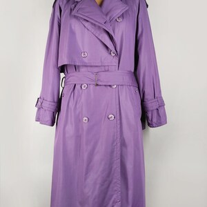 May include: A long, purple trench coat with a double-breasted closure, a belt, and a collar.