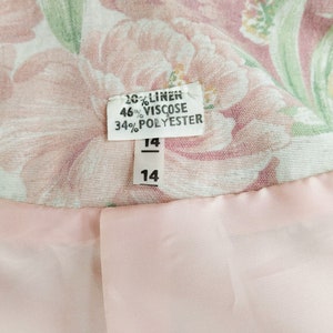 May include: A pink and green floral fabric with a white tag that reads "20% Linen, 46% Viscose, 34% Polyester" and a size tag that reads "14".