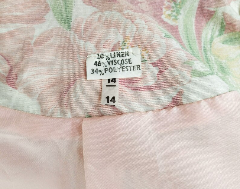 May include: A pink and green floral fabric with a white tag that reads "20% Linen, 46% Viscose, 34% Polyester" and a size tag that reads "14".