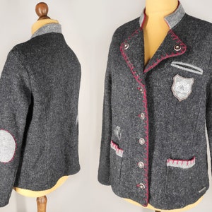 May include: A gray wool blazer with red stitching and a gray patch on the left side. The blazer has a collar and two pockets.