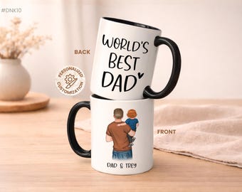 Könnte beinhalten: Zwei weiße Keramikbecher mit schwarzen Griffen und Rändern. Auf einem Becher steht "World's Best Dad" in schwarzer Schrift. Der andere Becher zeigt eine Illustration eines Vaters, der ein Kind hält, mit dem Text "Dad & Trey".