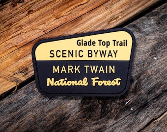 May include: A black and yellow patch with the text "Glade Top Trail Scenic Byway Mark Twain National Forest".