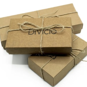 May include: Three brown cardboard boxes stacked on top of each other. The top box is tied with twine and has the word "Divicio" printed on it.