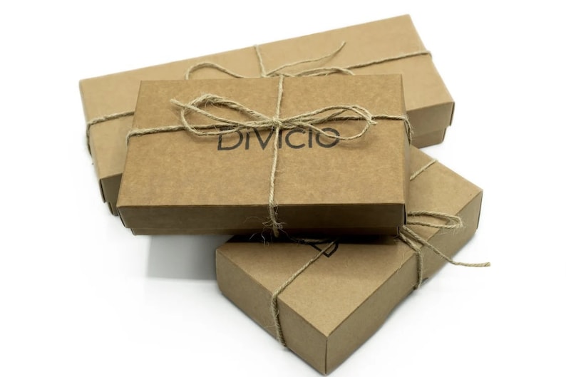 May include: Three brown cardboard boxes stacked on top of each other. The top box is tied with twine and has the word "Divicio" printed on it.
