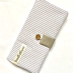 May include: A beige and white striped fabric clutch with a wooden button closure and a tan linen flap. The clutch has a label that reads "Famille Pleasant".