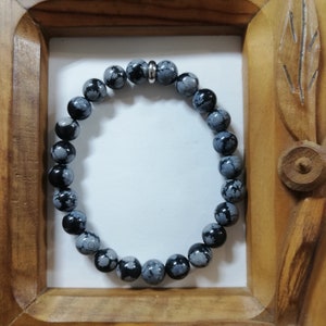 Op de afbeelding: Een armband van zwarte en witte gevlekte stenen kralen met een zilveren tussenkraal.