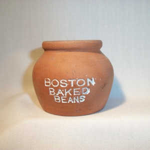 May include: A small, terracotta-colored ceramic jar with the words "BOSTON BAKED BEANS" written in white on the front.