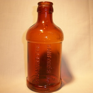 May include: An amber glass bottle with the text "SANFORD'S" and "ANDBERRY-FRASER" embossed on the side.
