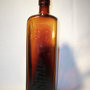 May include: A vintage amber glass bottle with a cork stopper. The bottle has the word "SMITH'S" embossed on the front.