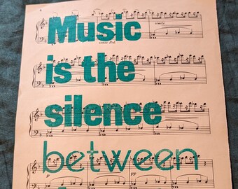 Music quote letterpress printed on old sheet music, "Music is the silence between the notes"