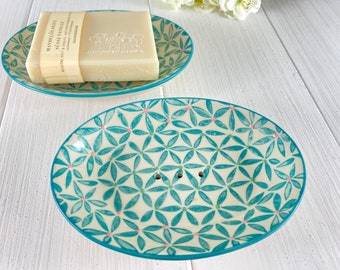Könnte beinhalten: Zwei ovale Keramik-Seifenschalen mit einem blauen und weißen Blumenmuster. Die obere Schale hat eine Seife darauf. Die untere Schale hat Abflusslöcher.
