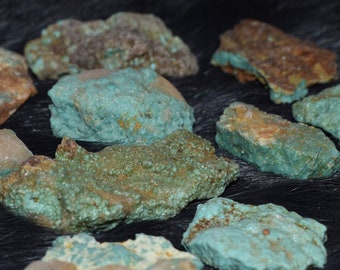 Pode incluir: Uma coleção de pedras turquesa em vários formatos e tamanhos. As pedras são uma mistura de cores verde e marrom.