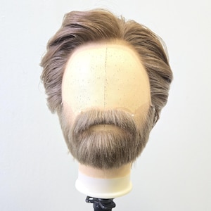 May include: A mannequin head with light brown hair and a matching beard and mustache. The hair is styled with a side part and slight wave. The mannequin is mounted on a black stand against a white background.