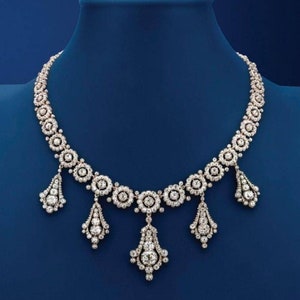 May include: A diamond necklace with a central row of round diamond clusters and three dangling teardrop-shaped diamond clusters.