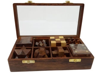 May include: A wooden box with a glass lid containing a set of nine wooden brain teaser puzzles. The puzzles are arranged in a grid pattern inside the box.