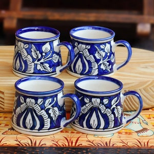 Peut inclure: Ensemble de quatre tasses en céramique bleu et blanc avec des motifs floraux. Les tasses ont une forme arrondie et une seule anse.