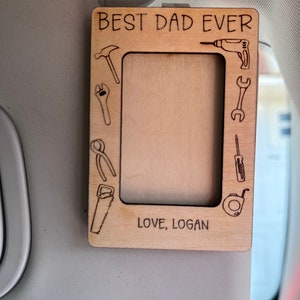 May include: A wooden photo frame with a cutout design of tools around the border. The frame says "BEST DAD EVER" at the top and "LOVE, LOGAN" at the bottom.