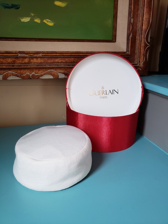 White, winter pill box style hat with red hat box