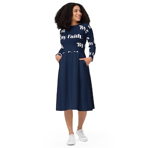 Könnte beinhalten: Ein marineblaues Midikleid mit langen Ärmeln und Taschen. Das Kleid zeigt den Schriftzug "By Faith" in weißen Buchstaben auf dem Oberteil und den Ärmeln. Die Person trägt weiße Turnschuhe.