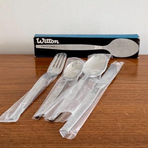 以下が含まれることがあります： 銀色のフォーク、スプーン、ナイフの3点セット。プラスチックで包まれ、青い箱に「Wilton」とラベルが貼られています。