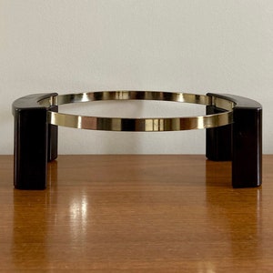 May include: A black metal stand with a round top and three legs. The stand is made of metal and has a polished finish.