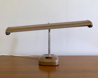 May include: A vintage desk lamp with a brown metal base and a long, rectangular shade. The lamp has a chrome arm and a red switch.