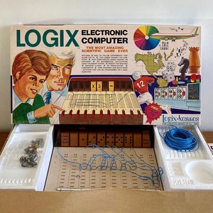 May include: An open box containing a Logix Electronic Computer game. The box features a colourful illustration of the game and the text "The Most Amazing Scientific Game Ever". The game includes a circuit board, wires, and other components.