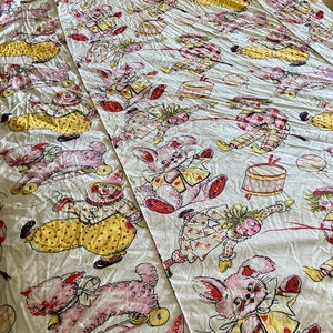 May include: A white cotton fabric with a repeating pattern of pink and yellow toy animals. The animals include a clown, a bunny, and a cat. The animals are all wearing clothes and have a whimsical, vintage look.