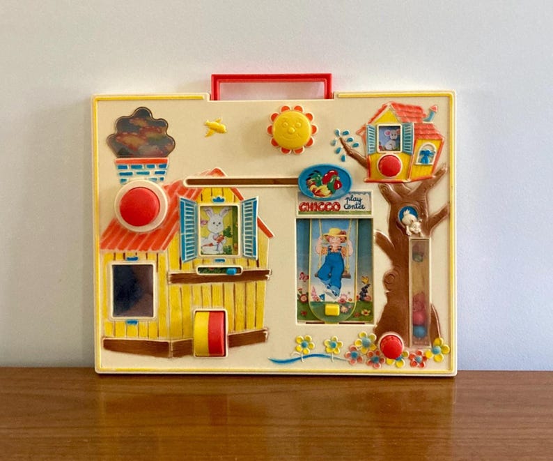 Puede incluir: Juguete infantil vintage con marco amarillo, asa roja y elementos interactivos. Incluye una casa, una casa en el &aacute;rbol y una ventana con un conejito. El juguete tiene un sol, flores y el texto "play centre CHICCO".