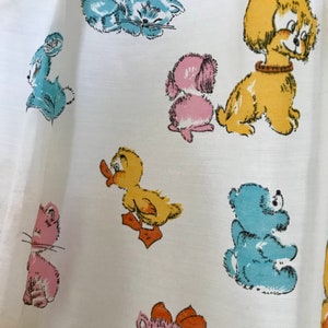 May include: White fabric with a repeating pattern of cartoon animals. The animals include a duck, a cat, a dog, a bear, and a rabbit. The animals are all in different colors, including blue, yellow, pink, and brown.
