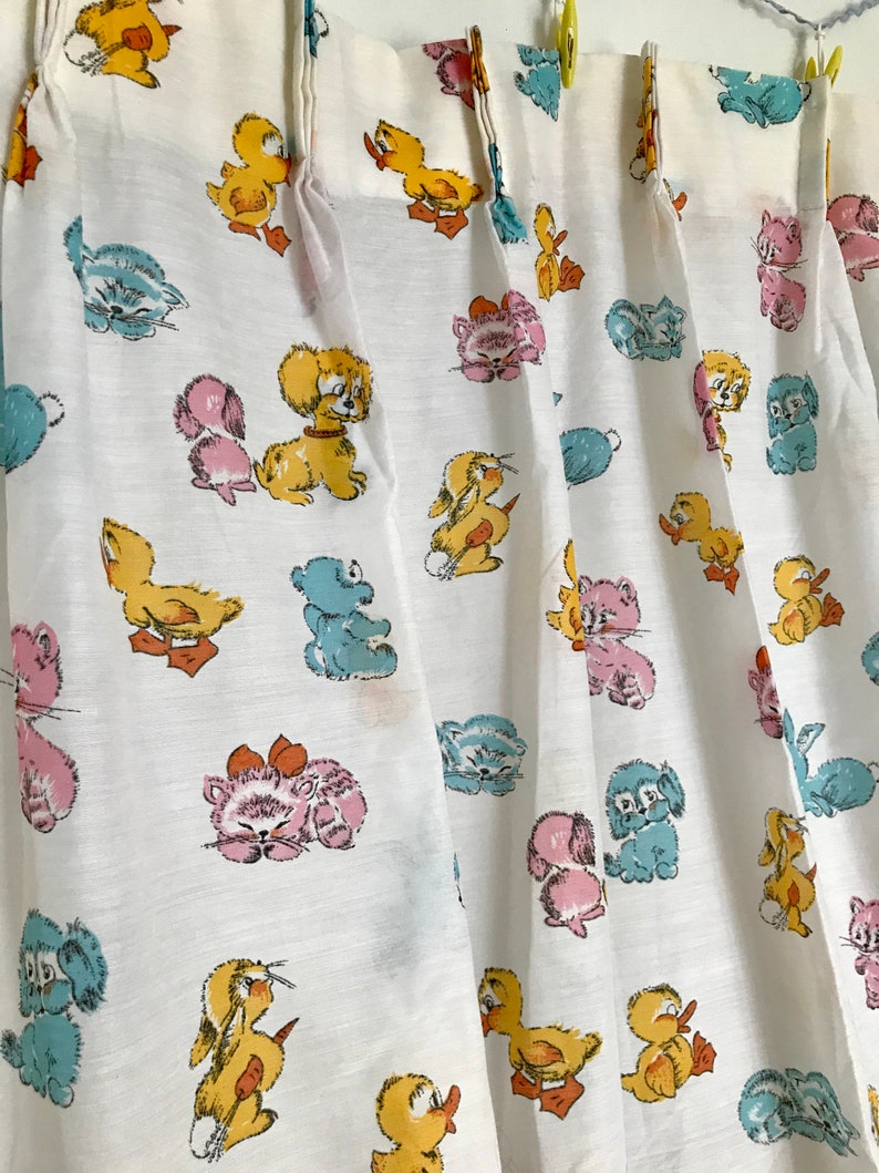 May include: White fabric curtains with a repeating pattern of cartoon animals, including ducks, kittens, puppies, and bunnies. The animals are in shades of yellow, pink, blue, and brown.