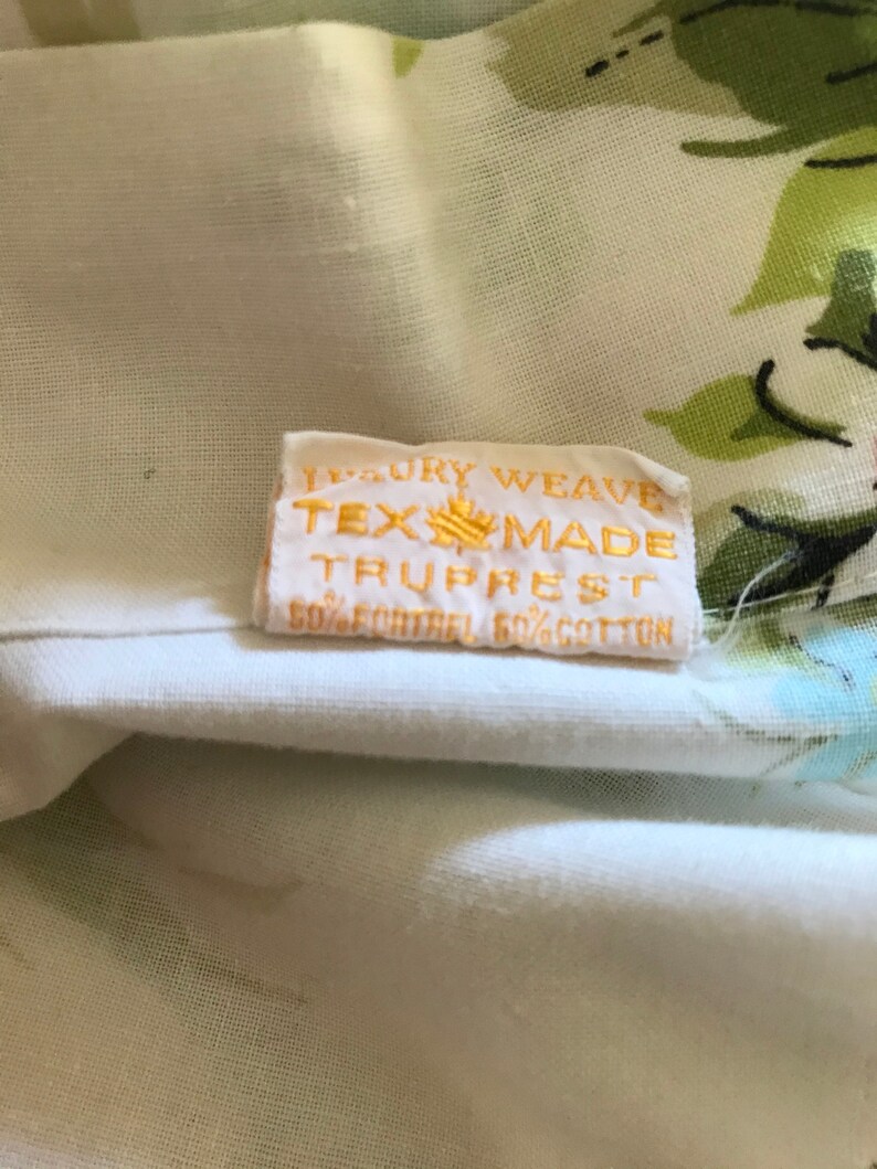 Puede incluir: Una tela blanca con un patr&oacute;n floral y una etiqueta amarilla que dice "Luxury Weave Tex-Made Truprest 50%  Contrel 50% Cotton".