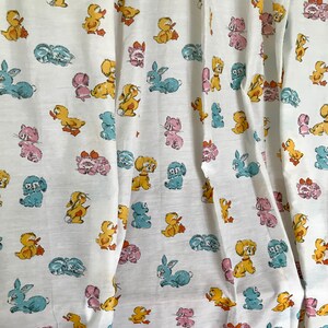 May include: White fabric with a repeating pattern of cartoon animals. The animals include ducks, bunnies, cats, and dogs in various colors, including pink, blue, yellow, and orange.